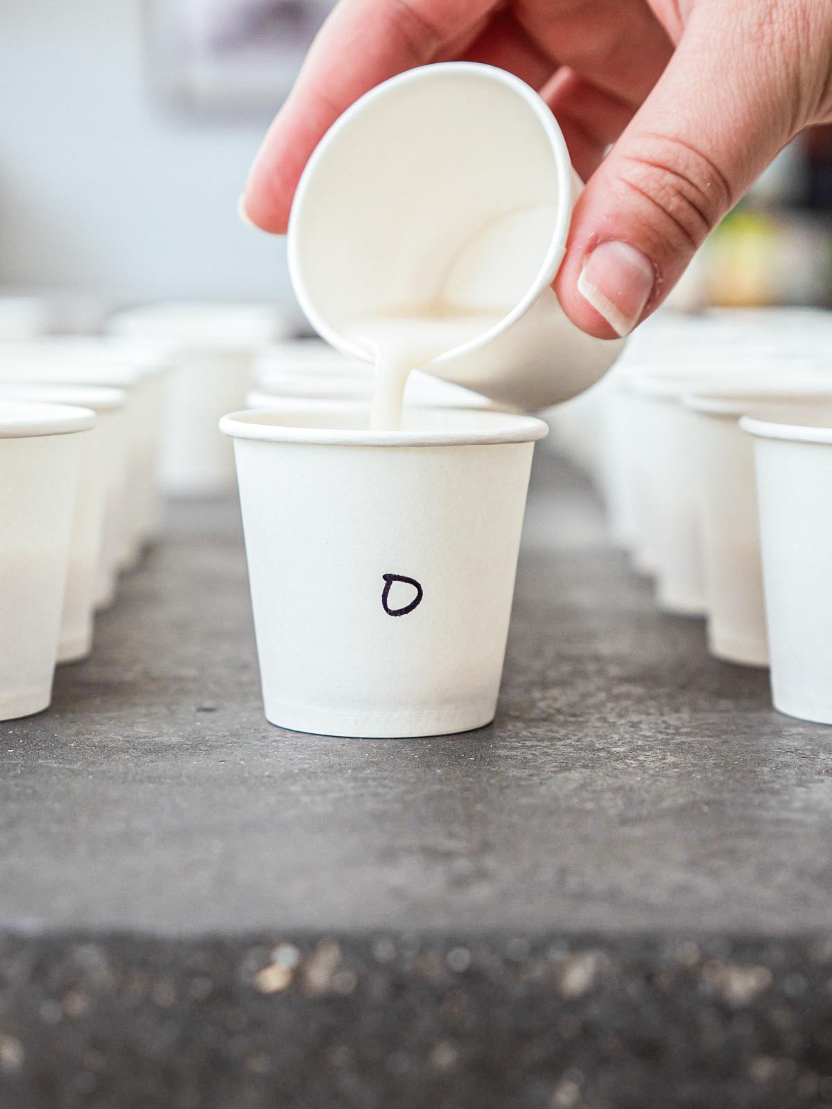 Pouring almond milk brand into test cup.