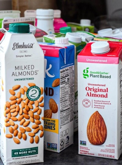 Different brands of almond milk on a counter top.