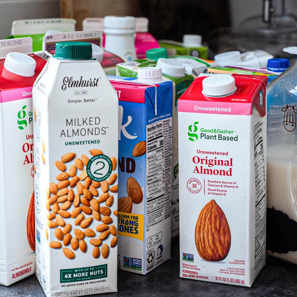 Different brands of almond milk on a counter top.