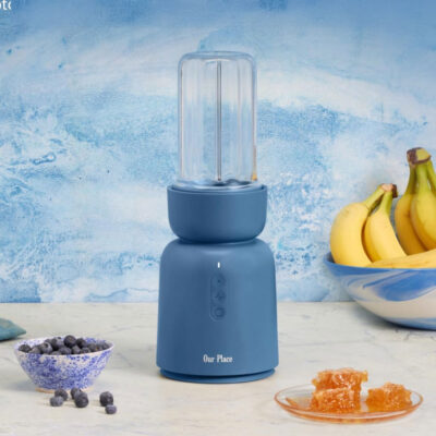 Our Place blender for smoothies on counter with bowl of berries and bananas.
