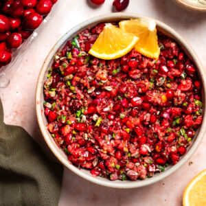 Bowl of cranberry relish with decorative orange wedges.
