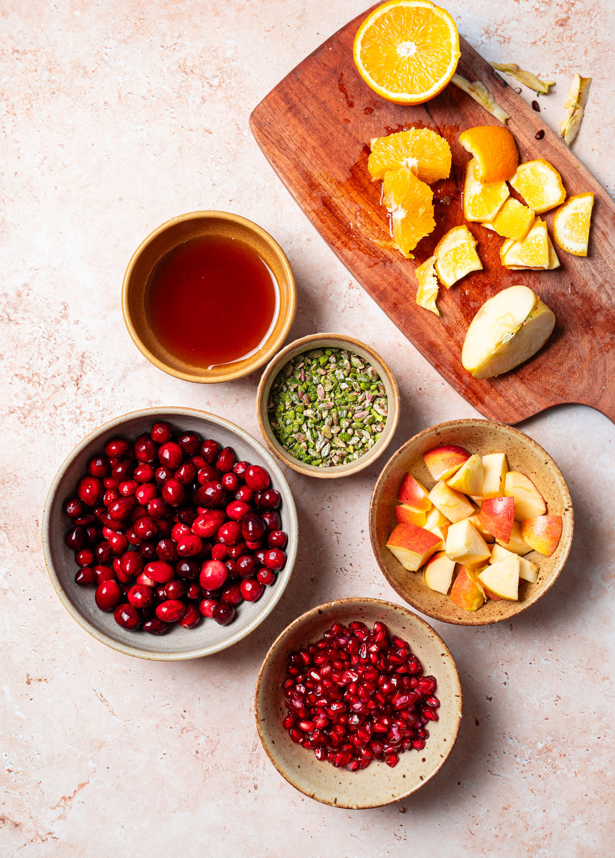 Fresh ingredients to make homemade cranberry relish recipe like cranberries, pistachios, apples and oranges.