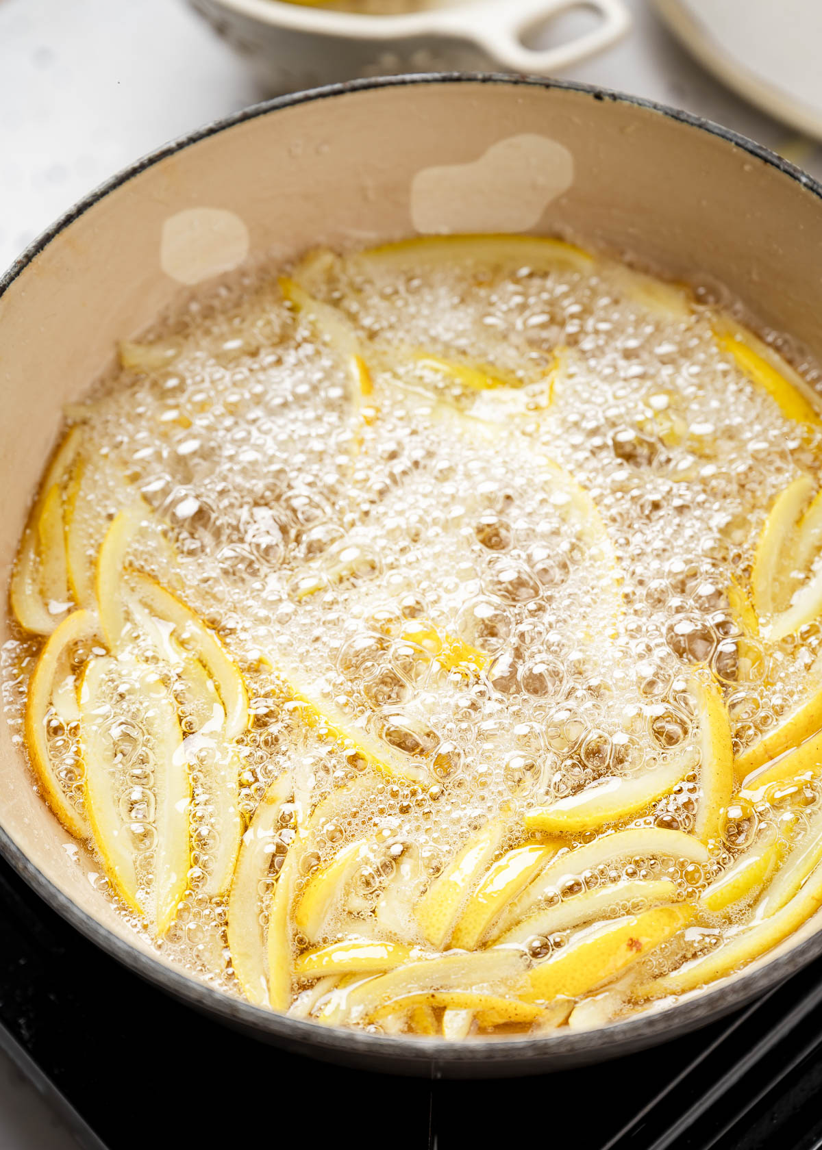 Candied lemon peels simmering in a pot.
