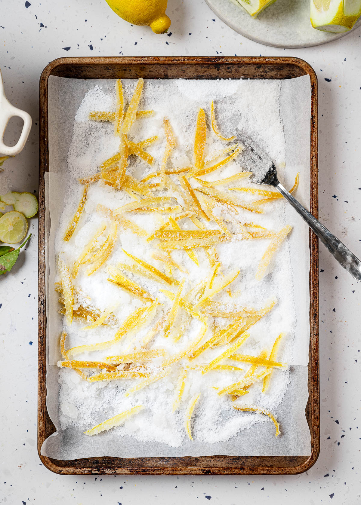 Candied lemon peels on a sugar-coated baking sheet.