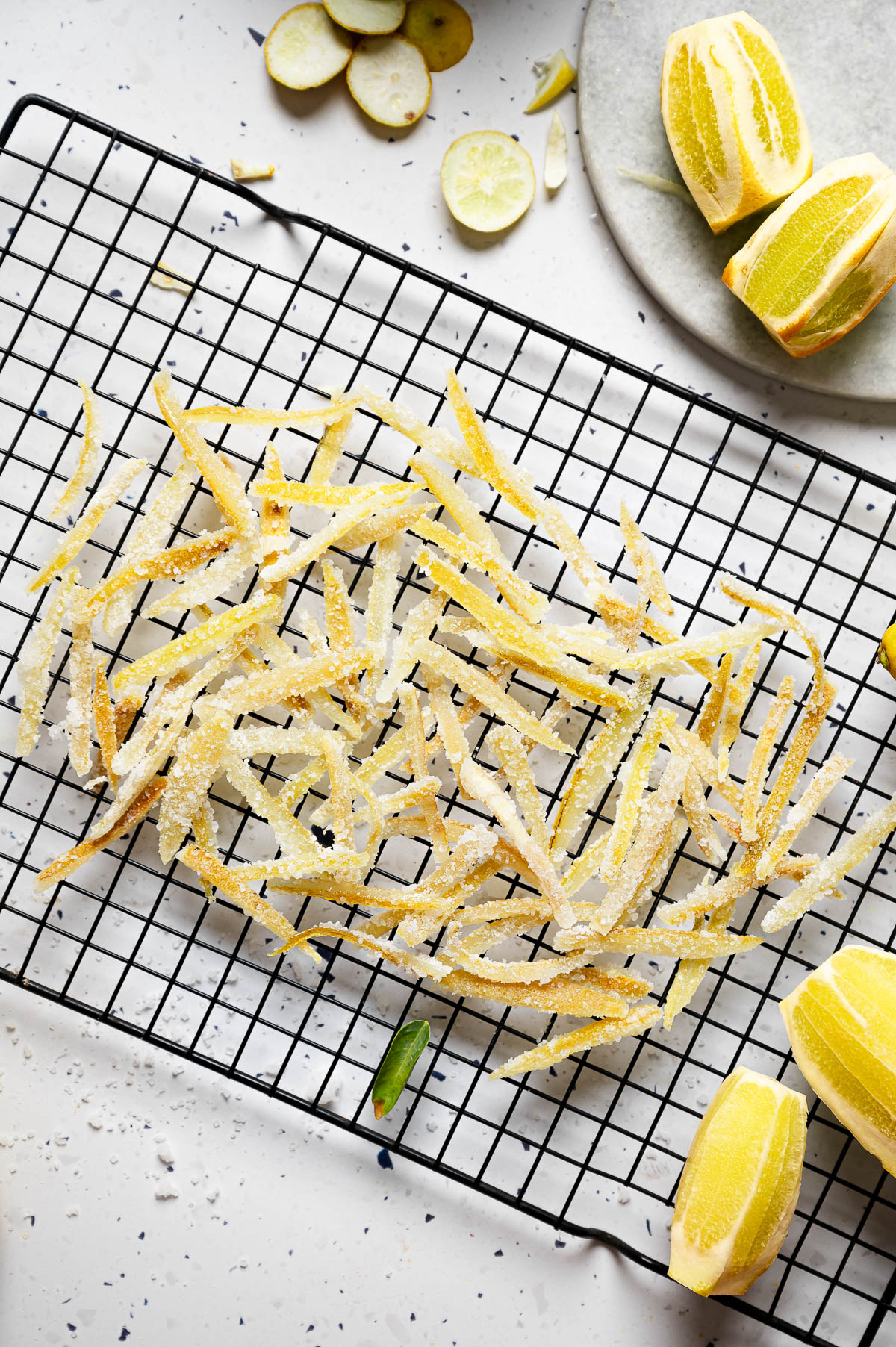 Candied lemon peels spread out on a wire rack.