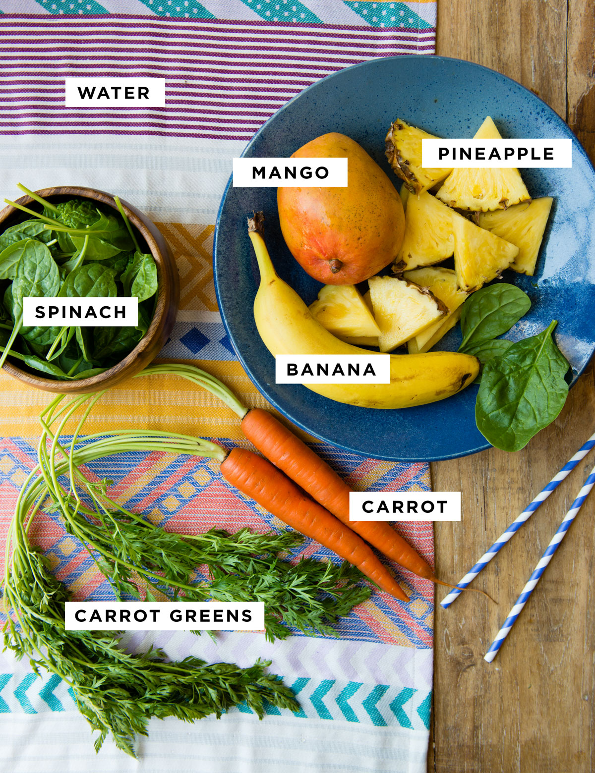 Ingredients for a carrot greens smoothie with carrot tops, mango, pineapple, banana, and spinach.