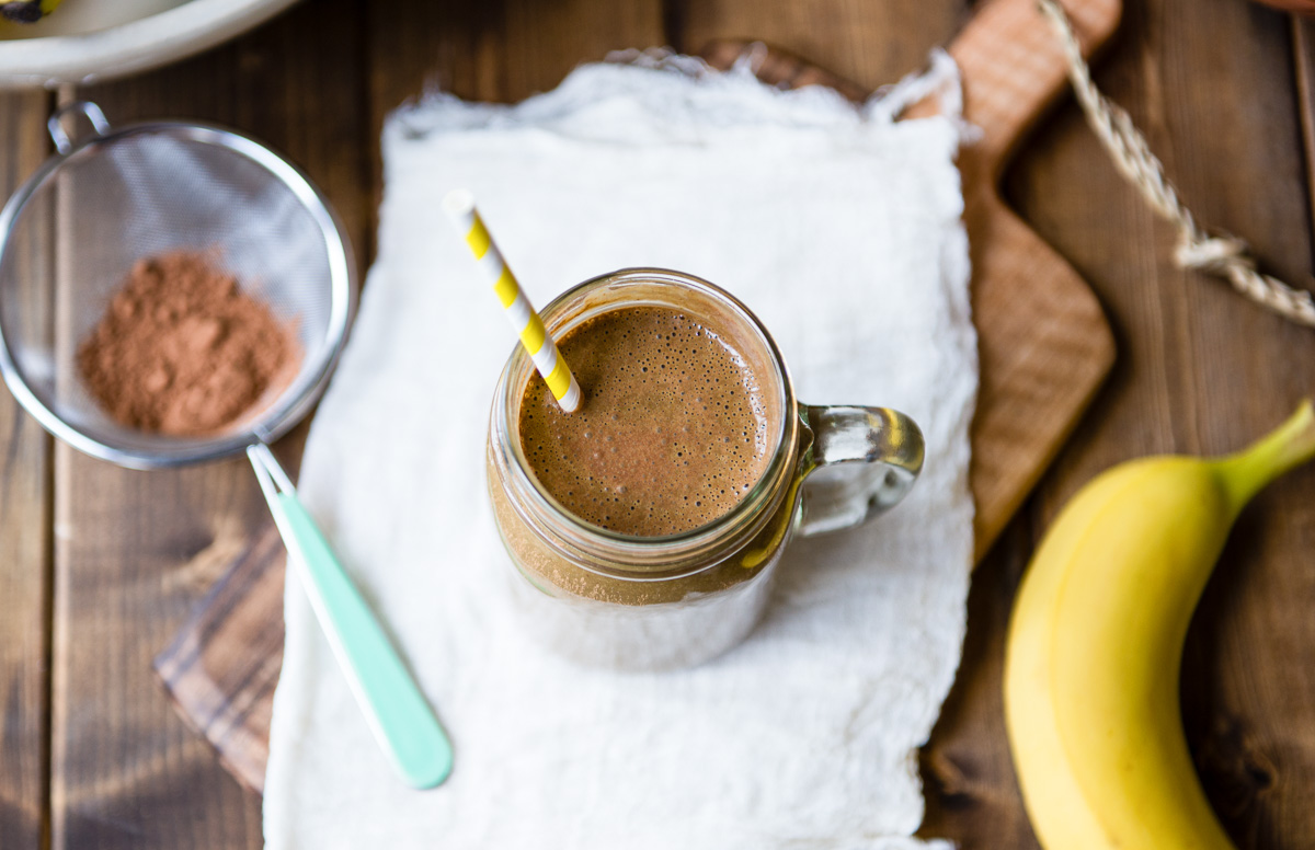 Chocolate banana smoothie in a glass jar mug with a striped straw.