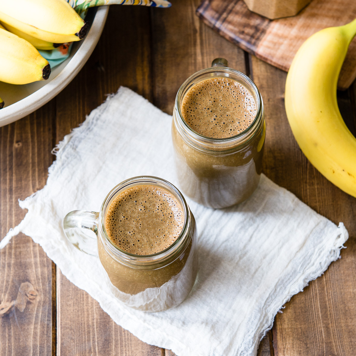 Two glass jars full of chocolate banana smoothie.