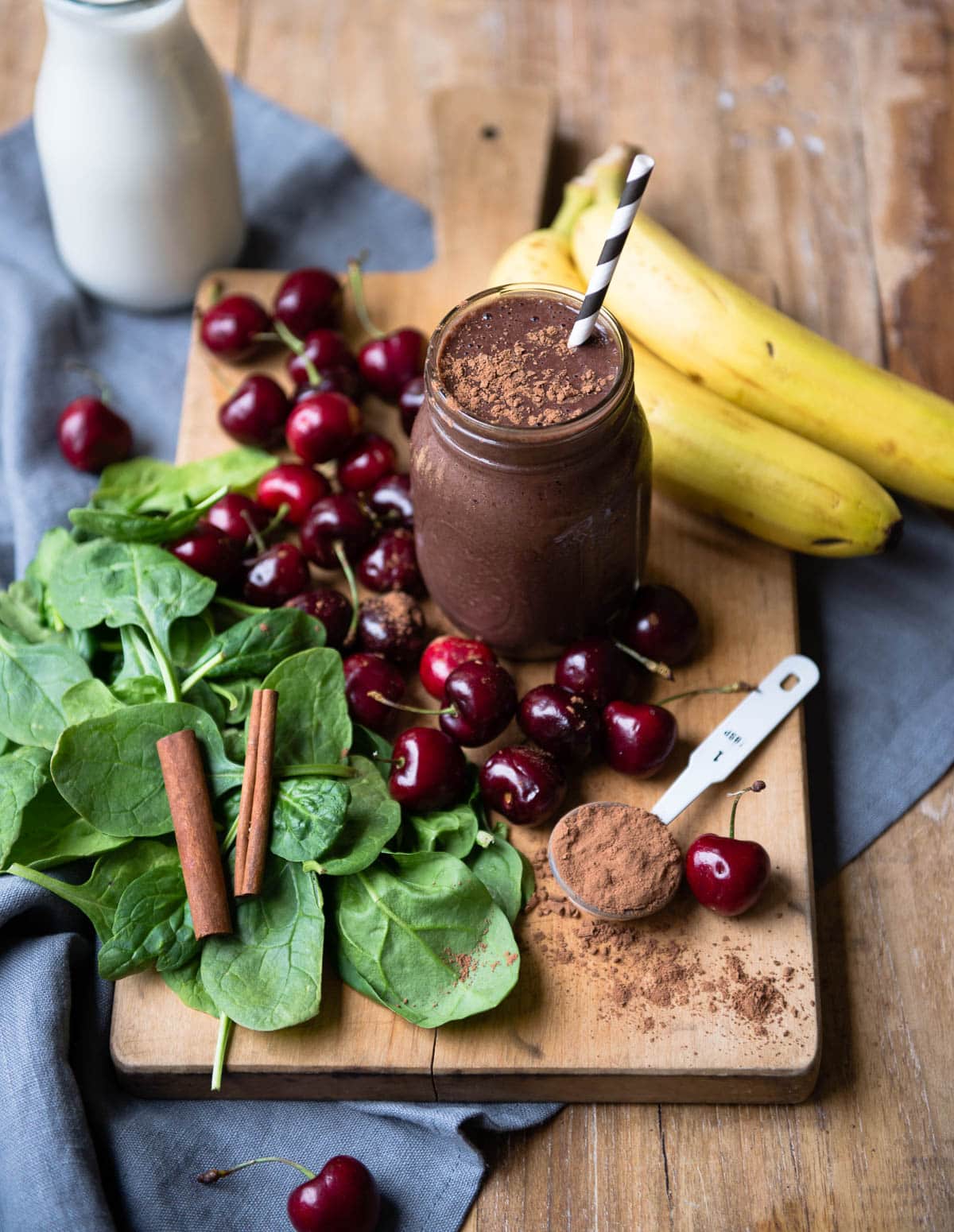 A chocolate cherry smoothie in a glass jar with fresh ingredients.