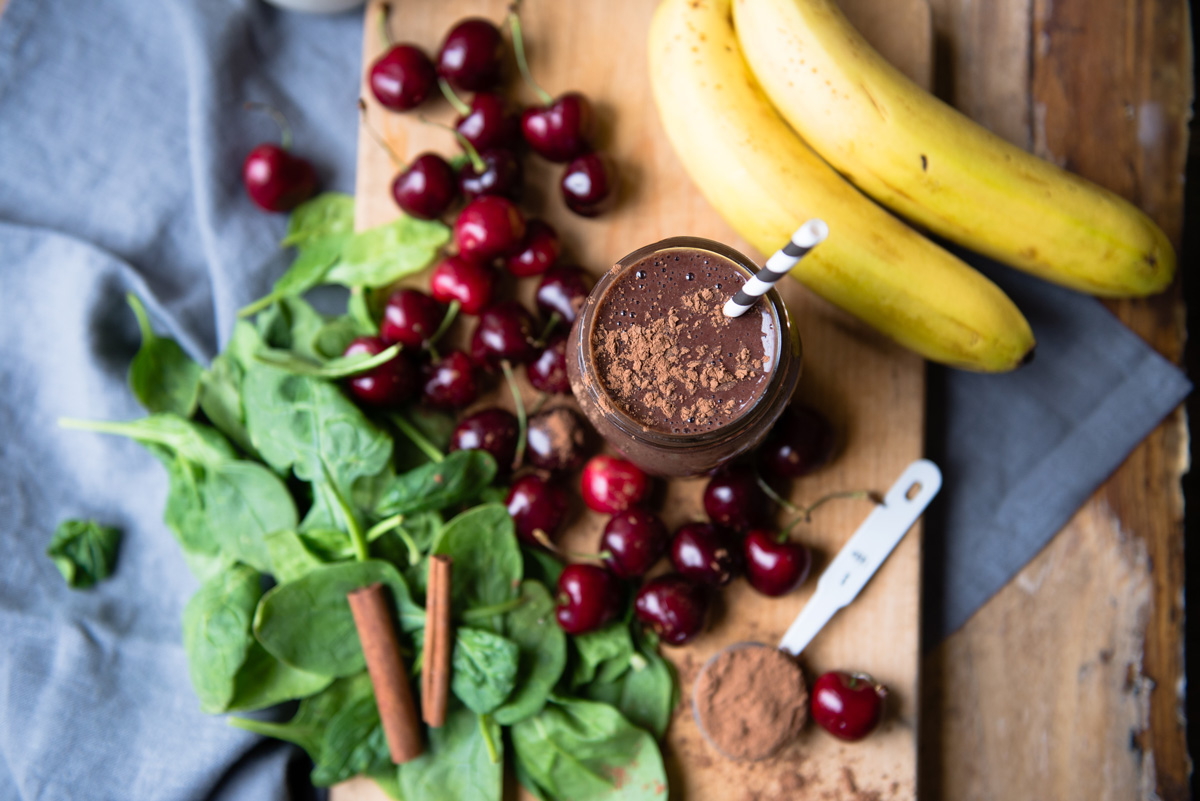 Glass of chocolate cherry smoothie in kitchen with straw.