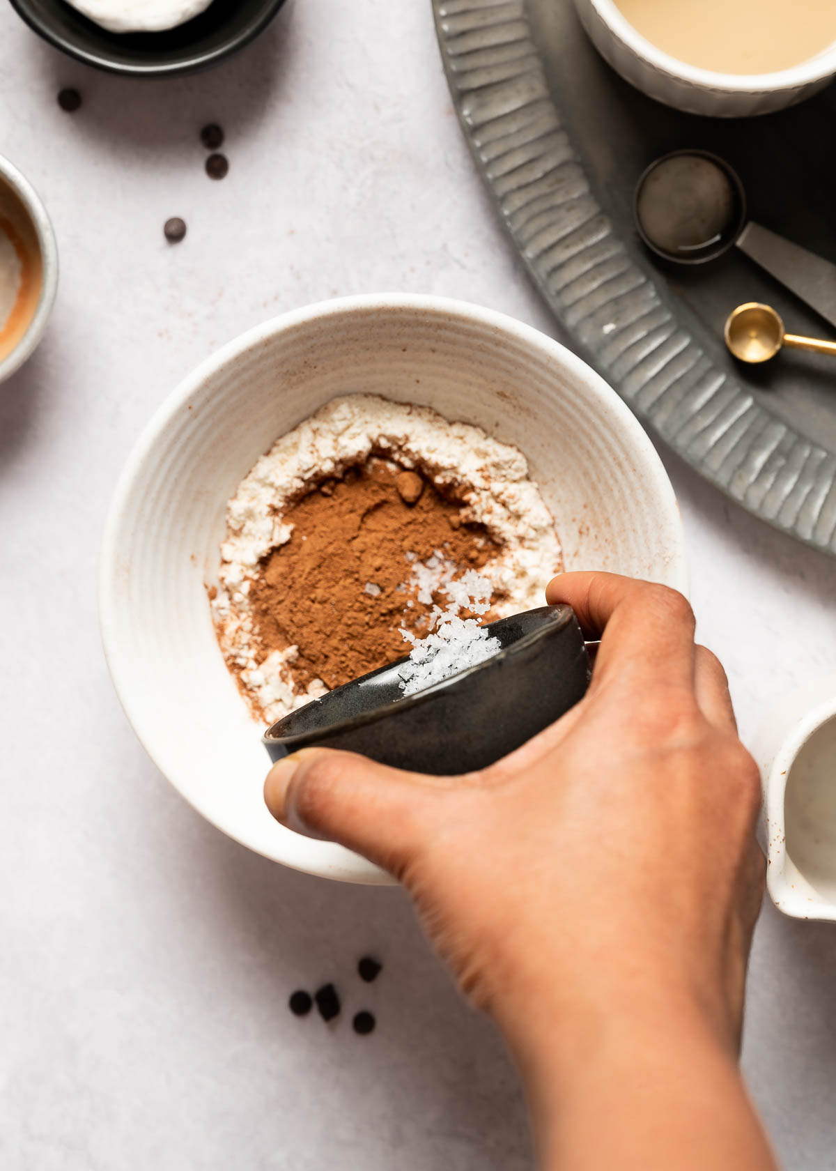 Pouring salt into bowl of flour, cacao and baking powder.