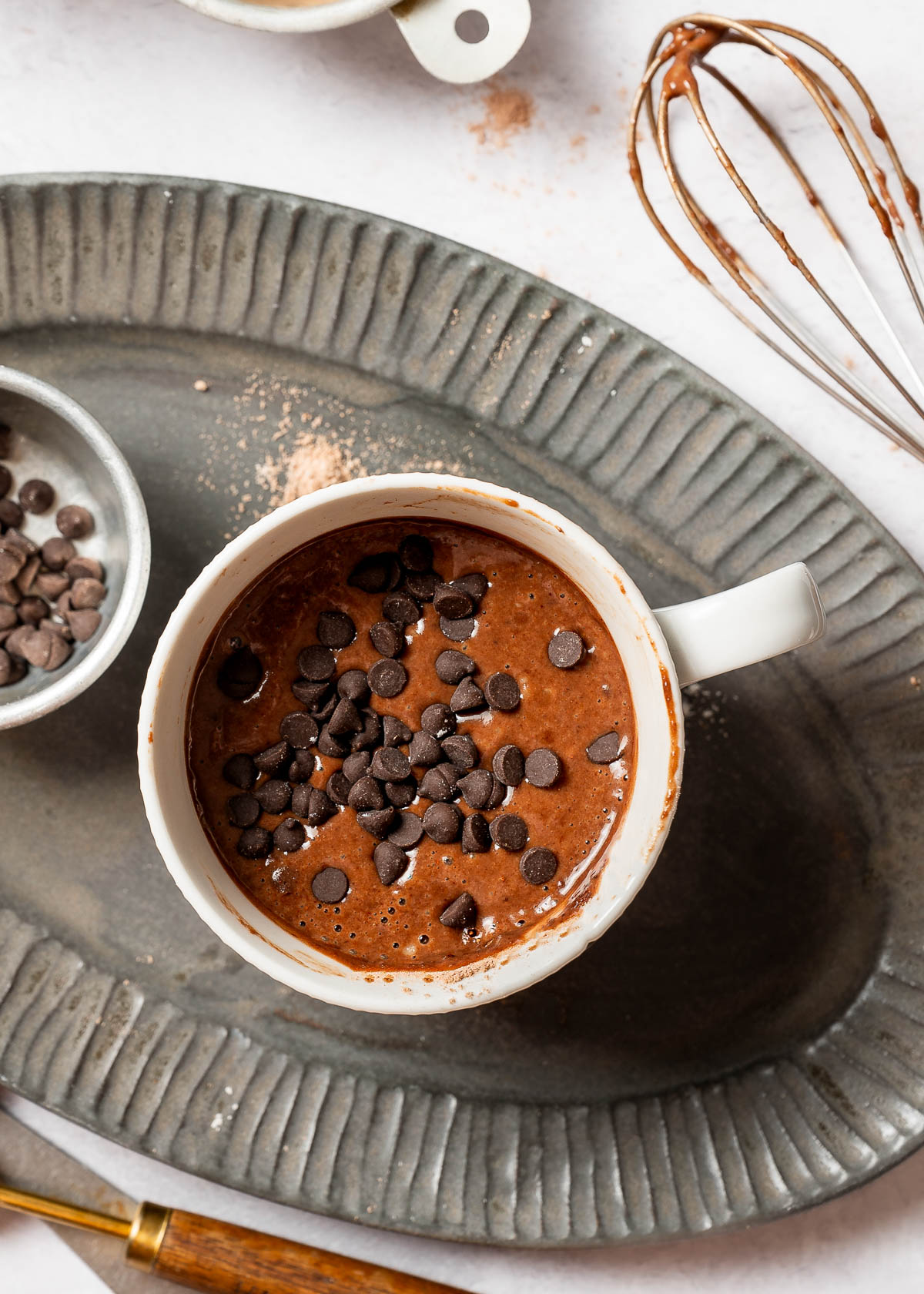 Coffee cup with vegan chocolate chips sprinkled on top to make mug cake.