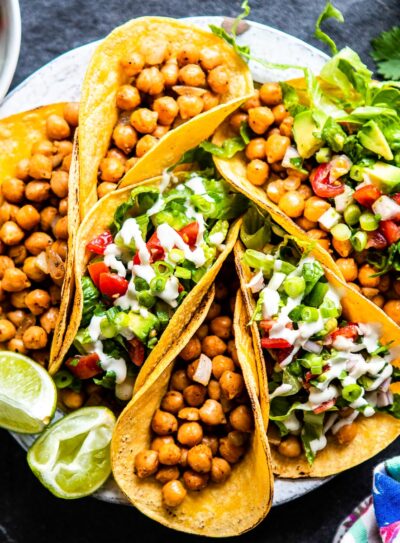 A plate full of chickpea tacos with fresh toppings.