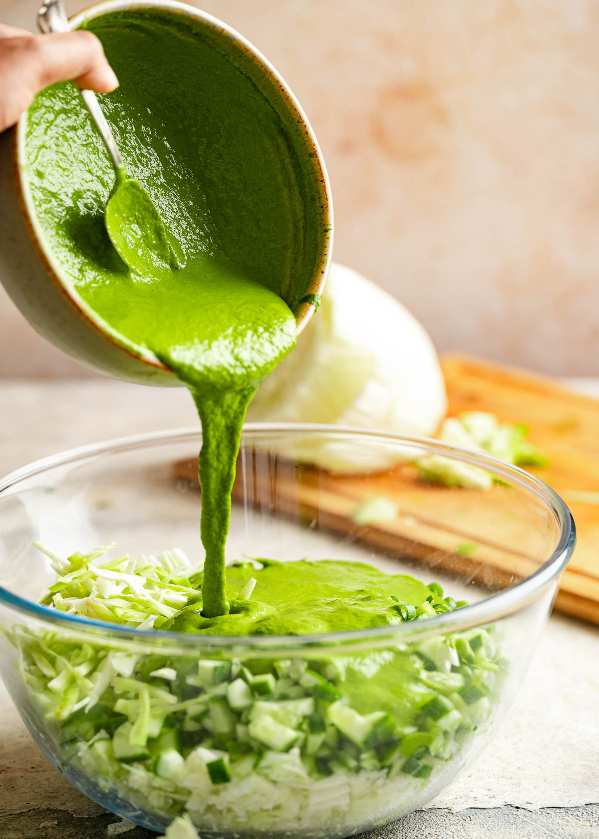 A person drizzling dressing over a bowl of salad.