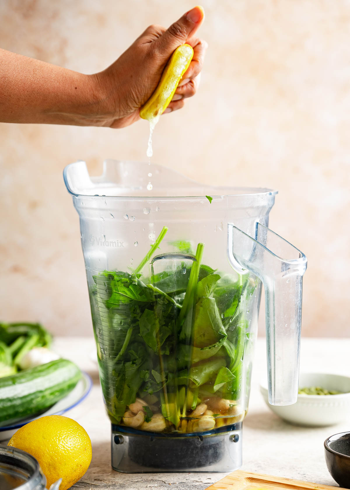 A person squeezing fresh lemon over the green goddess dressing ingredients.