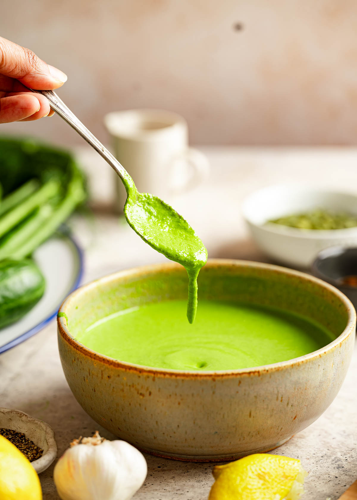 Green goddess dressing drips from the spoon back into the bowl.