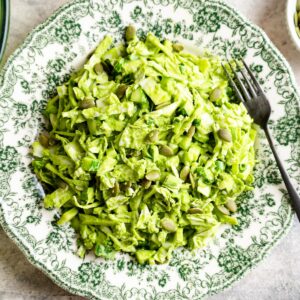 Ready to eat green goddess salad on a green and white plate.