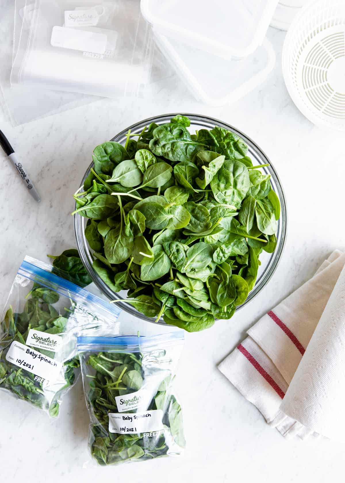 A bowl of fresh spinach next to labeled bags of fresh spinach. 