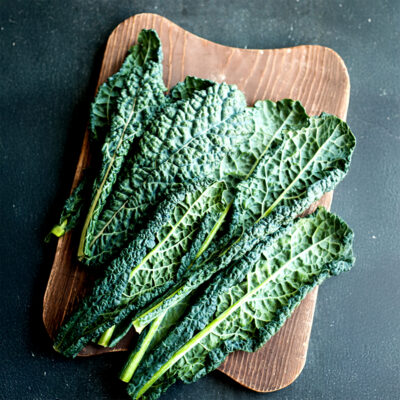 Lacinato kale leafy greens on wood cutting board.