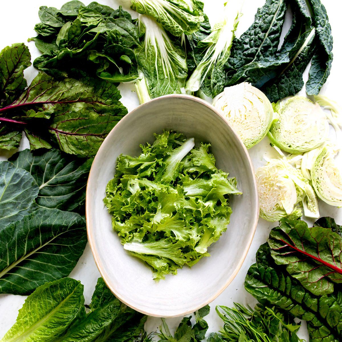 Bowl with romaine surrounded by leafy greens.