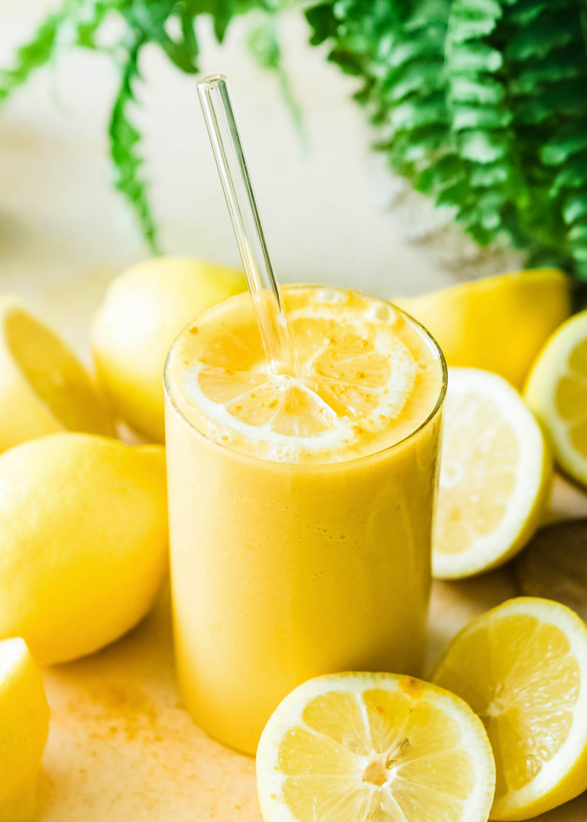 Lemon smoothie in medium glass with a glass straw. 