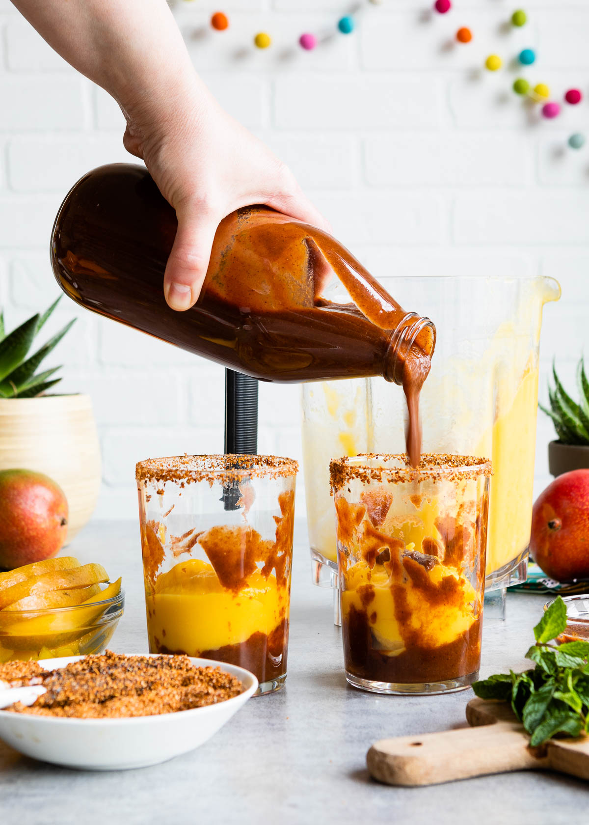 Chamoy sauce being poured into glasses of Mangonada. 