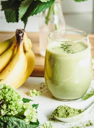 A vanilla matcha smoothie surrounded by fresh ingredients.