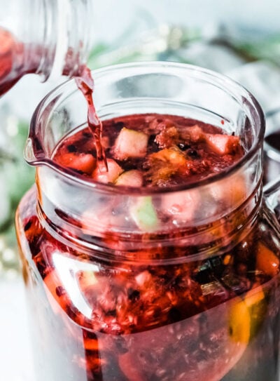 A person preparing non-alcoholic sangria in a glass jug