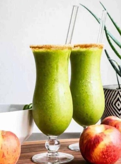 2 probiotic smoothies in cocktail glasses rimmed with coconut sugar and glass straws.