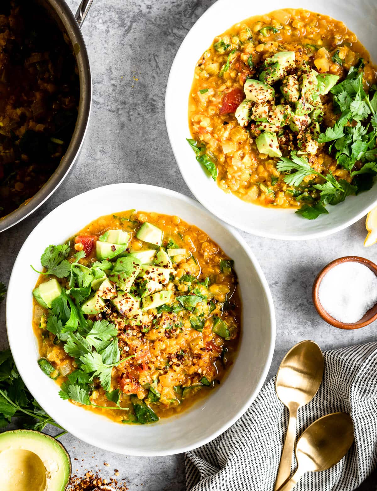 bowl of red lentil soup ron table with gold spoons.