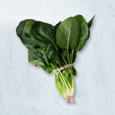 Fresh spinach in a bundle on table with leafy greens.
