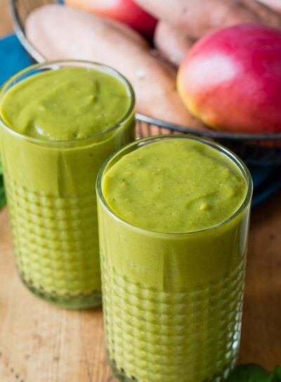 Two glasses of sweet potato smoothie on a table with fresh ingredients.