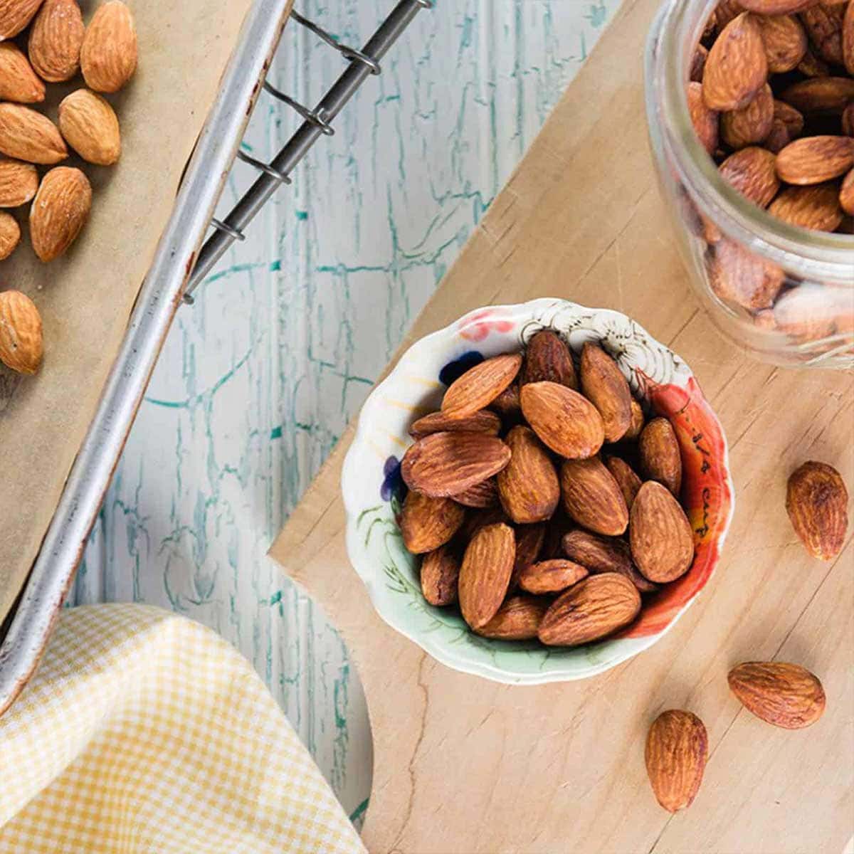 oven roasted almonds in a colorful snack bowl on a wooden tray.