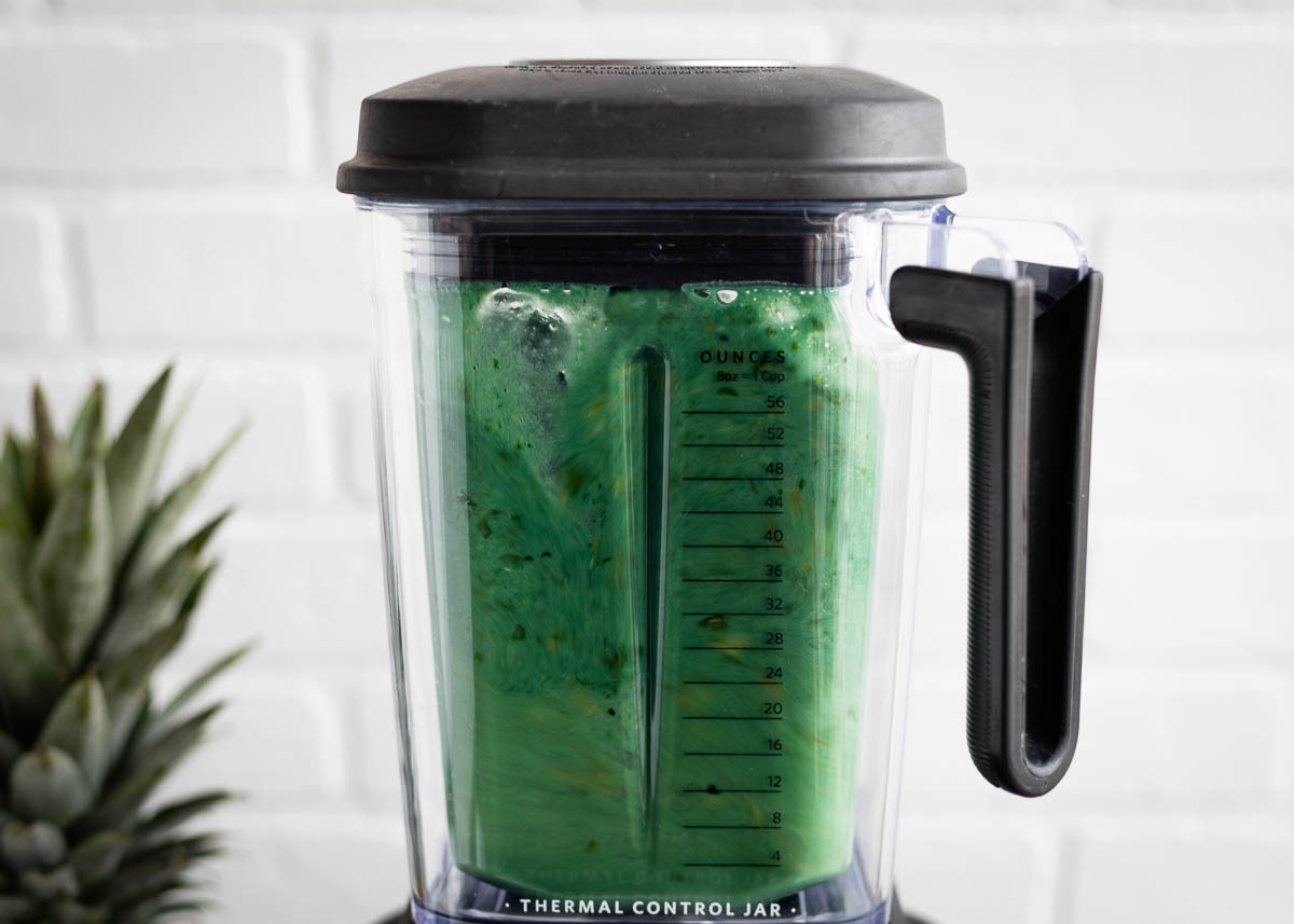 Green spirulina smoothie in a blender.