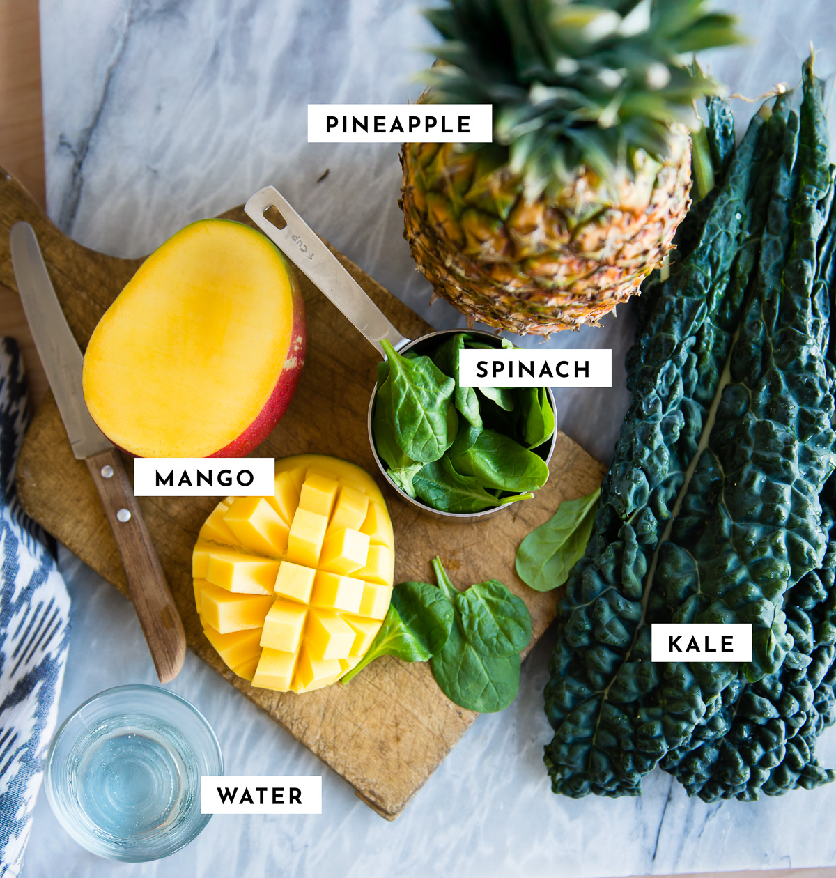 Ingredients for tropical detox smoothie on table with knife and cutting board.