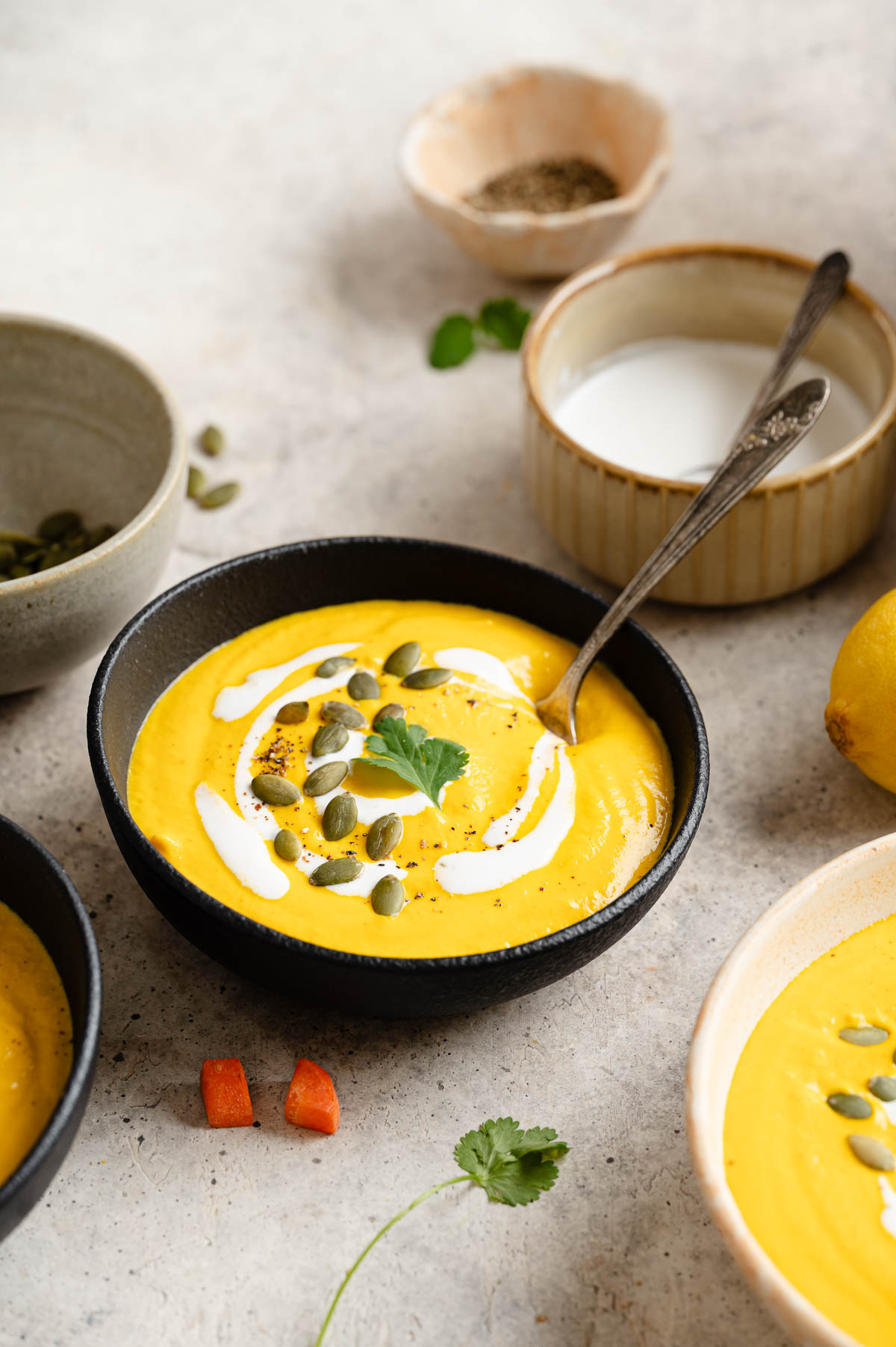 Table setting with carrot ginger soup and bowls of toppings.