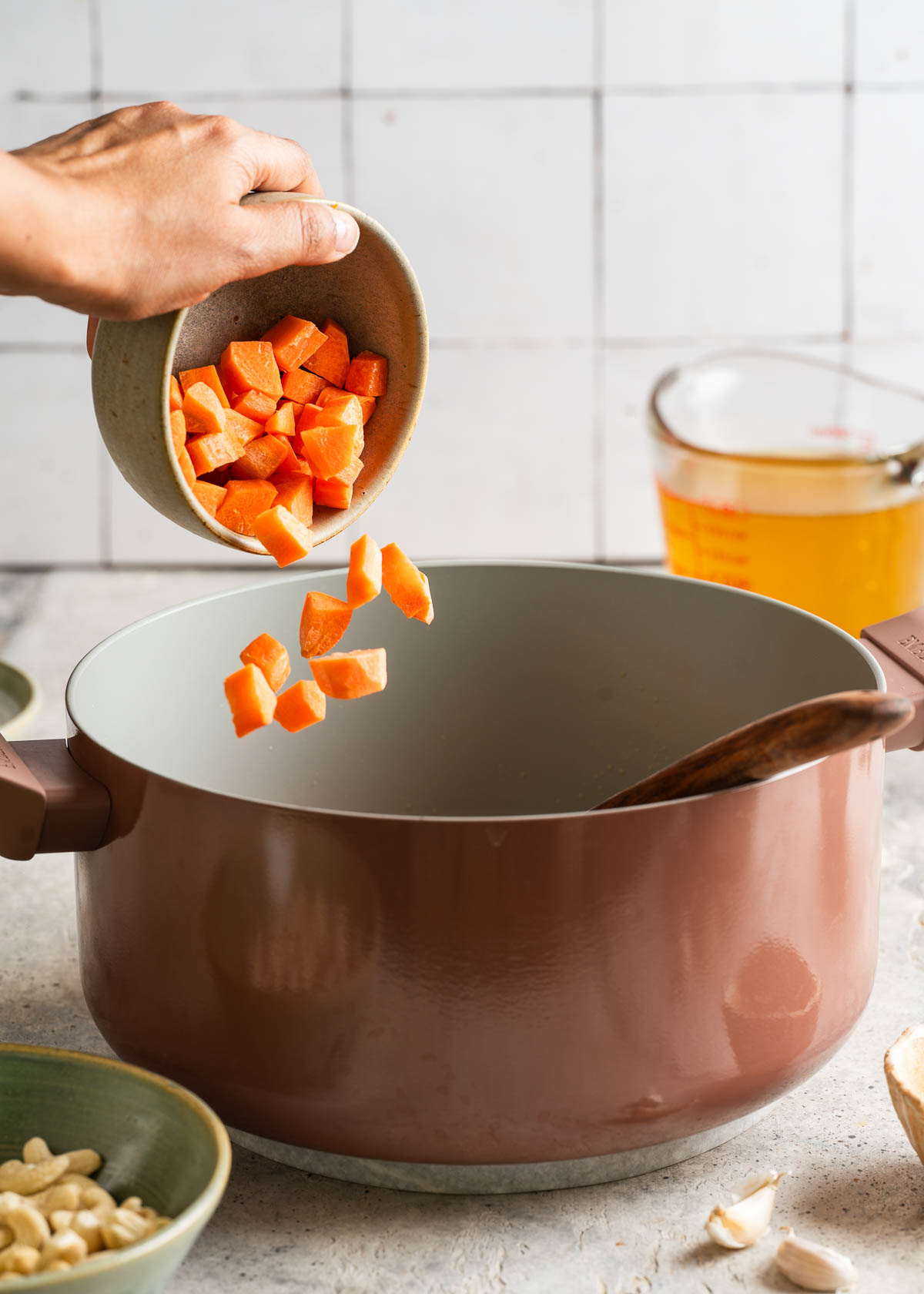 Tossing carrots into a pot of hot vegetable broth.