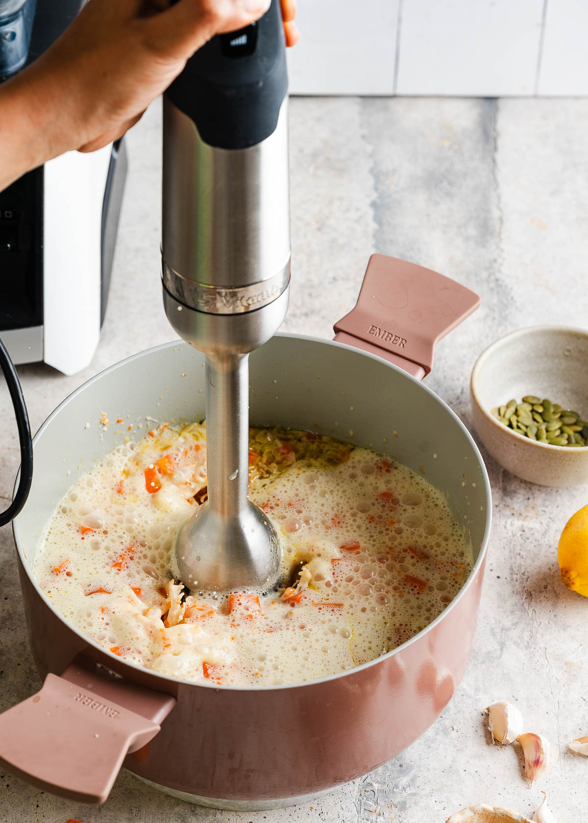 Blending vegan carrot ginger soup with an immersion blender.
