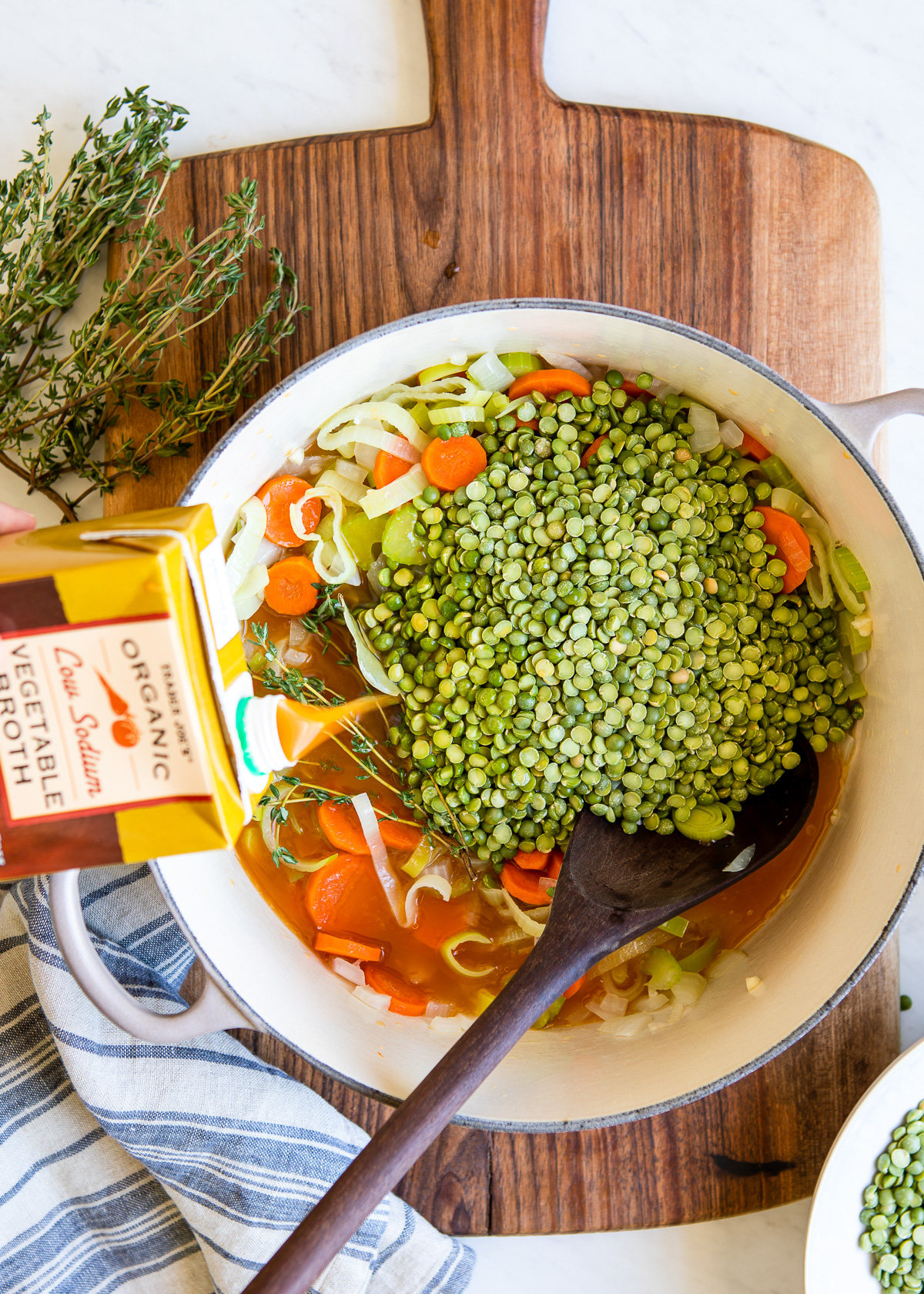 Pouring vegetable broth into pot of vegetarian split pea soup.